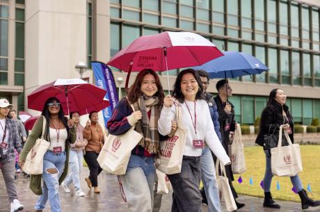 a group pf young adults holding umbrellas walking in the rain