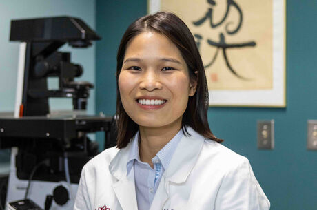 A doctor in a white lab coat smiles at the camera